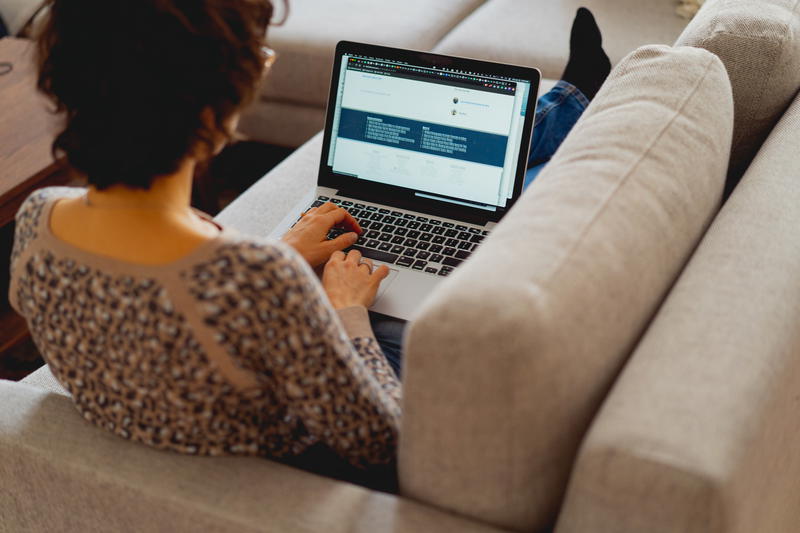 Woman working on a couch with a laptop with stickers