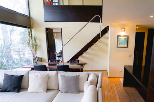 Modern minimalist home setup with white walls, black staircase, large floor to ceiling windows and a neat couch