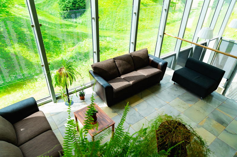 Brown couch on a tiled floor next to floor to ceiling windows with a grassy yard