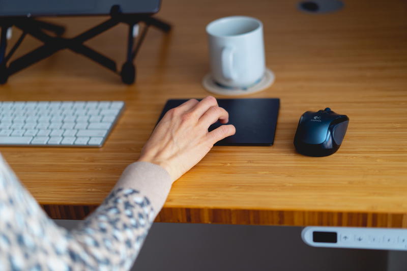 Woman working from home using the apple magic trackpad to comfortably work from home at a desk in a home office