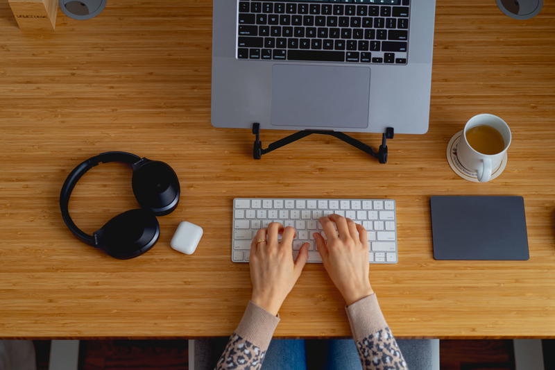 A woman's hands typing on a keyboard at a desk.