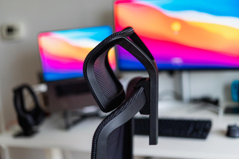 A black computer chair with two monitors in front of it.