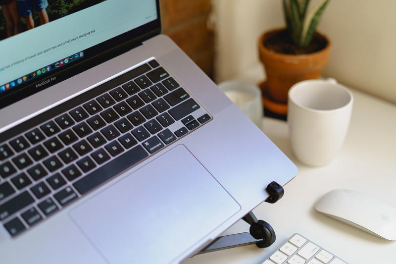 Close-up of black laptop stand holding silver MacBook Pro in a small apartment home office