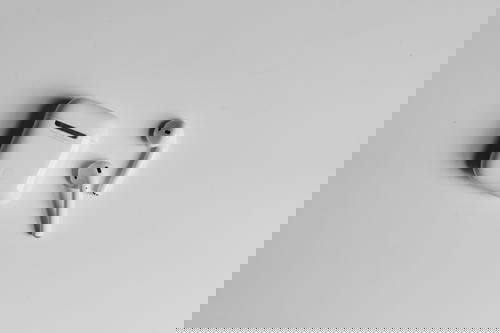 Apple Airpods case and 2 AirPod buds on a white table with shadows