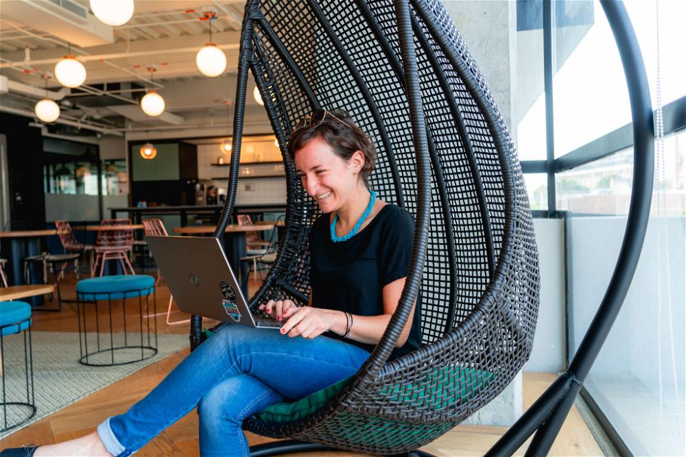 Woman working in a hanging chair in a coworking space