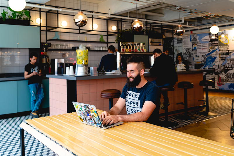 Man working on laptop in a WeWork communal cafeteria social area