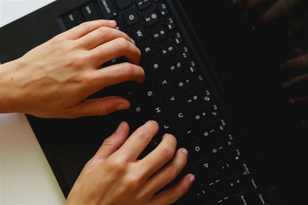Woman typing on the keyboard of a small sized Dell XPS laptop while working from home in a home office