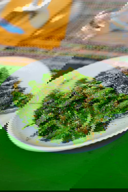 Burmese tea leaf salad on a white plate on a green table at a cooking class