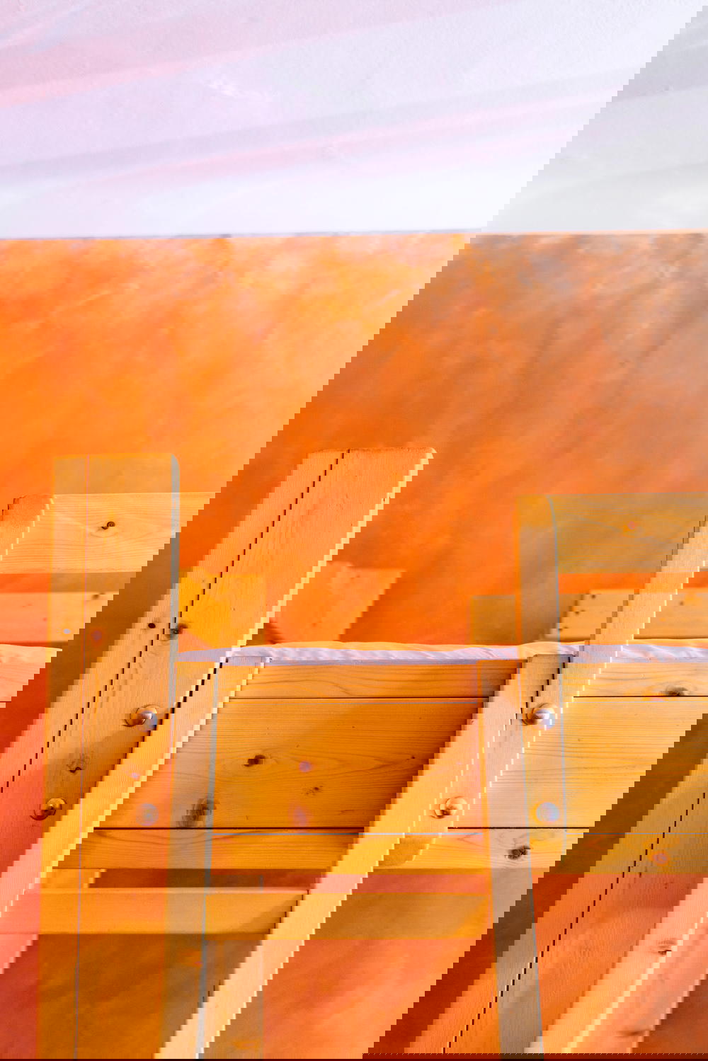 A bunk bed in a room with an orange wall.