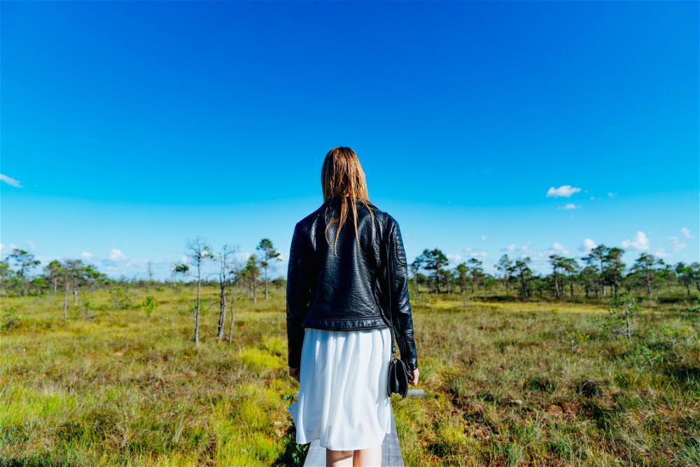Woman facing blue sky and bog scenery in Kemeri National Park