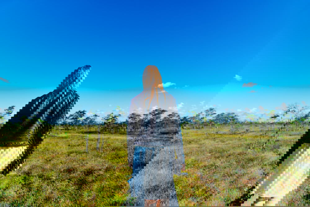 Woman facing blue sky and bog scenery in Kemeri National Park
