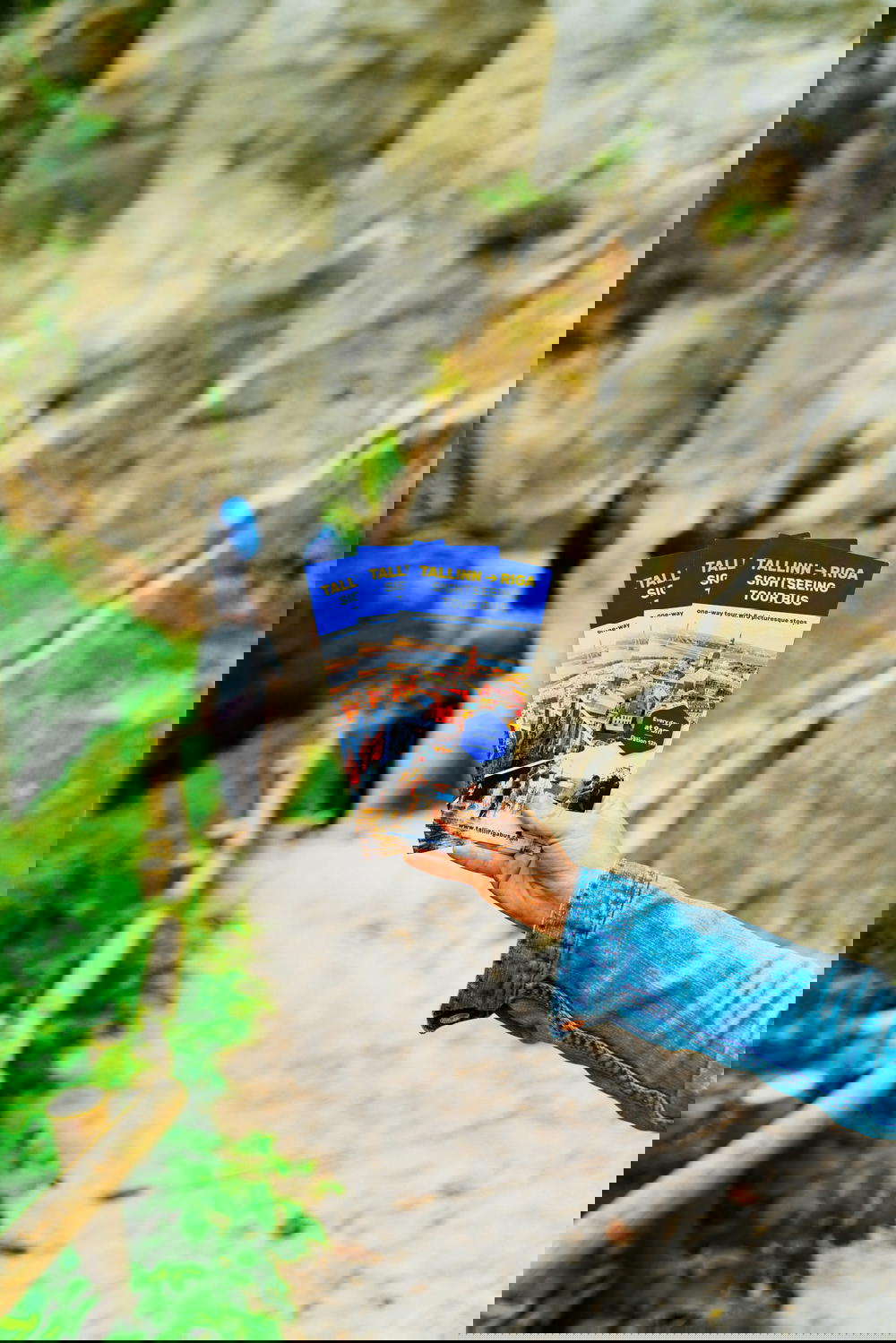 A woman holding up a book in front of a cliff.
