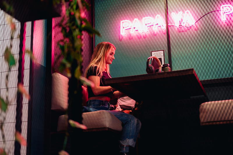 Woman working in a coworking space against a green wall with a neon sign