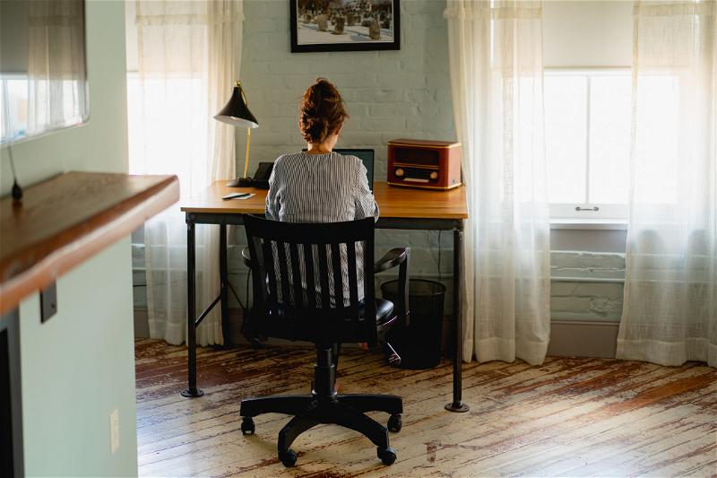 A woman sitting at a desk in front of a window.