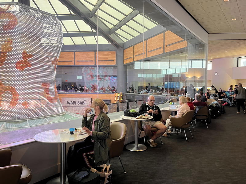 A group of people sitting at tables in an airport.