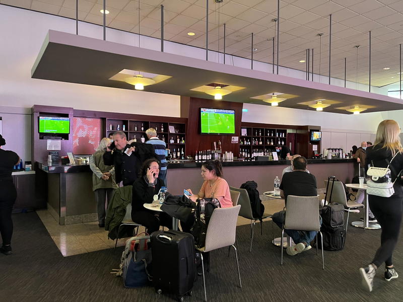 A group of people sitting at a bar in an airport.