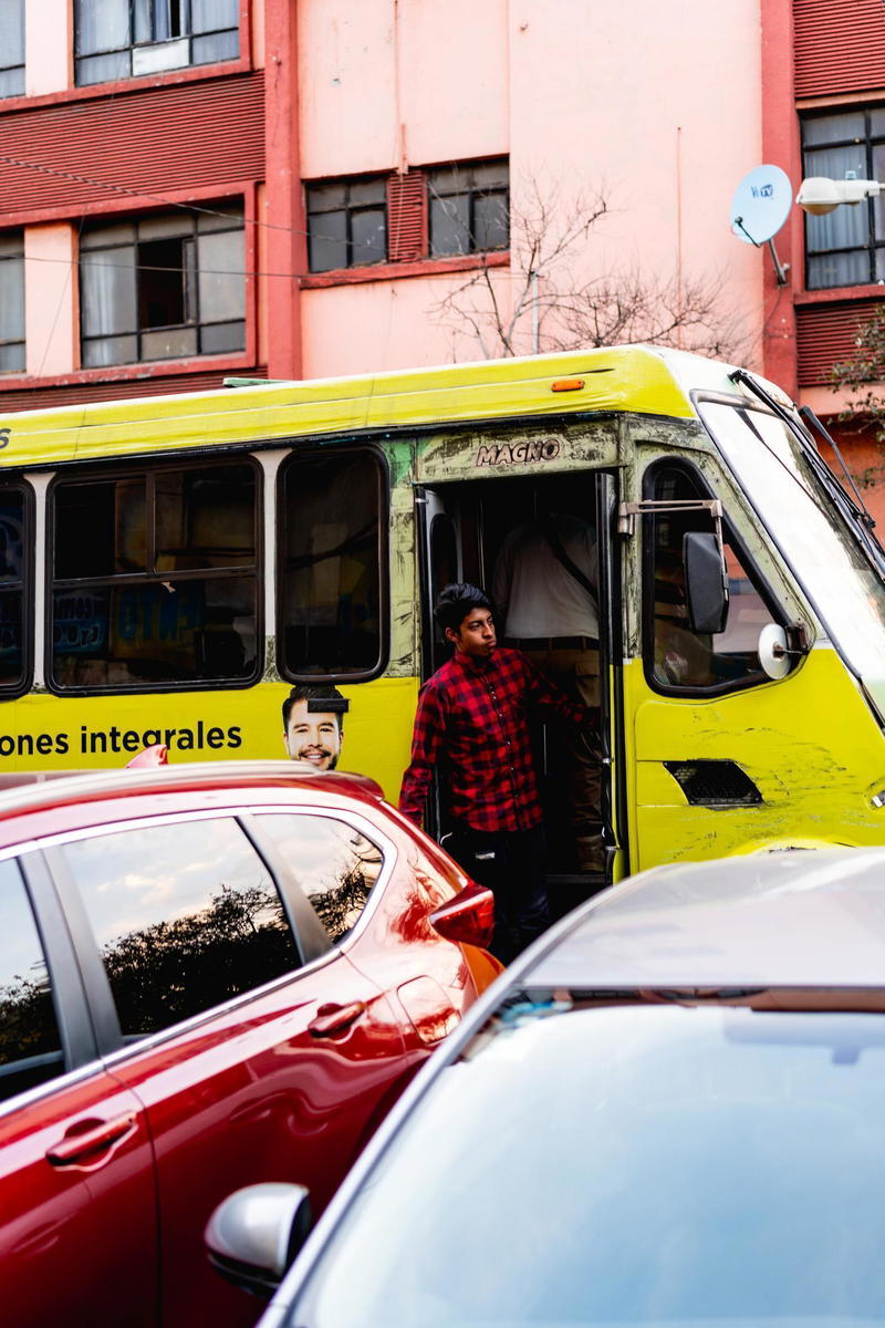 A red car parked next to a yellow bus.