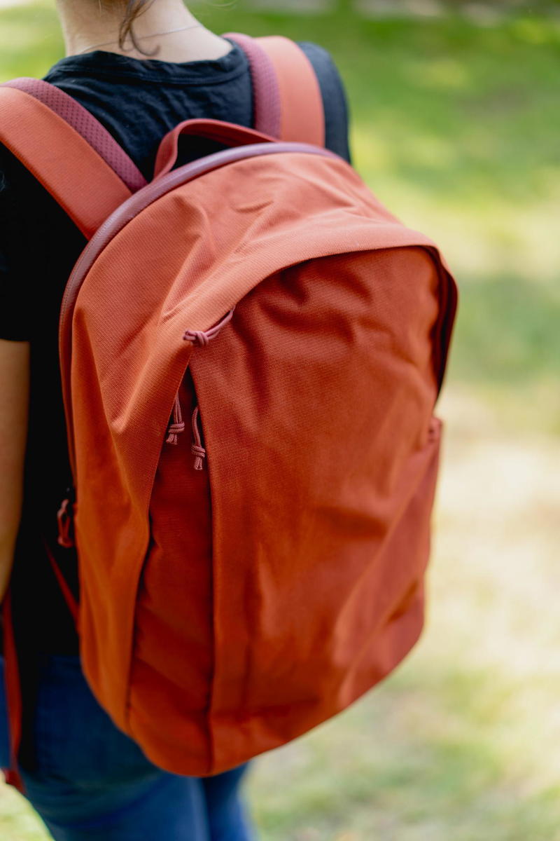 A woman wearing a Moment MTW Backpack in the park.