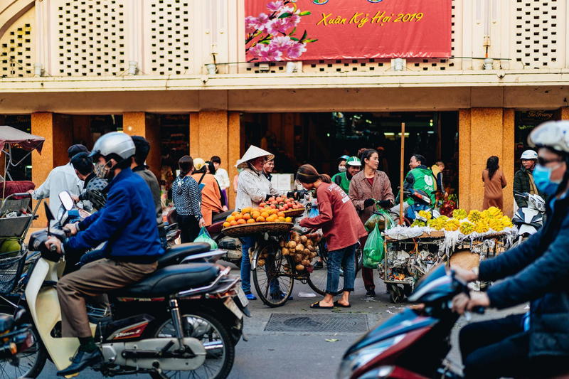 A group of people riding motorbikes in front of a building.