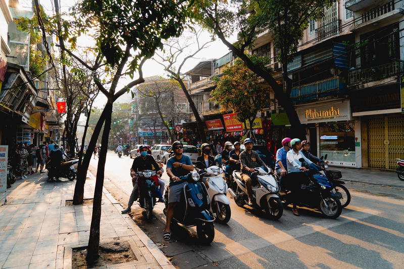 A group of people riding motorbikes down a street.