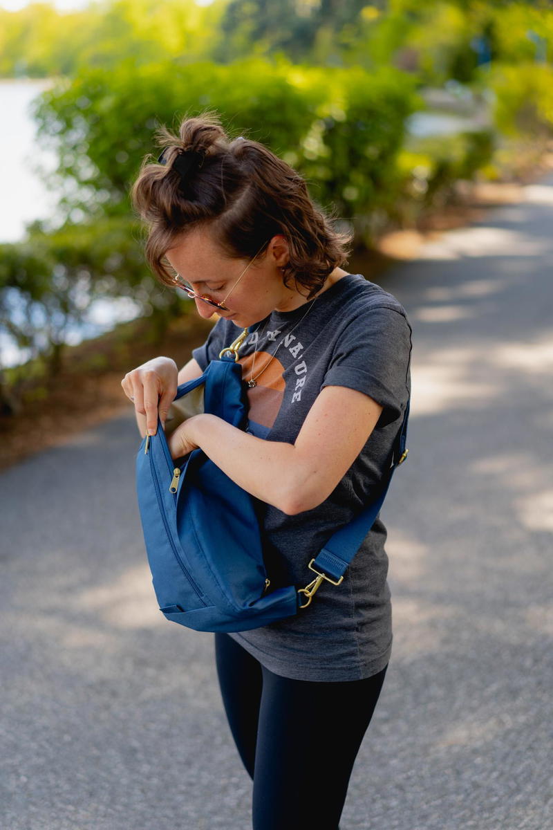 A woman holding a Canvelle Oversized Fanny Pack on a sidewalk.