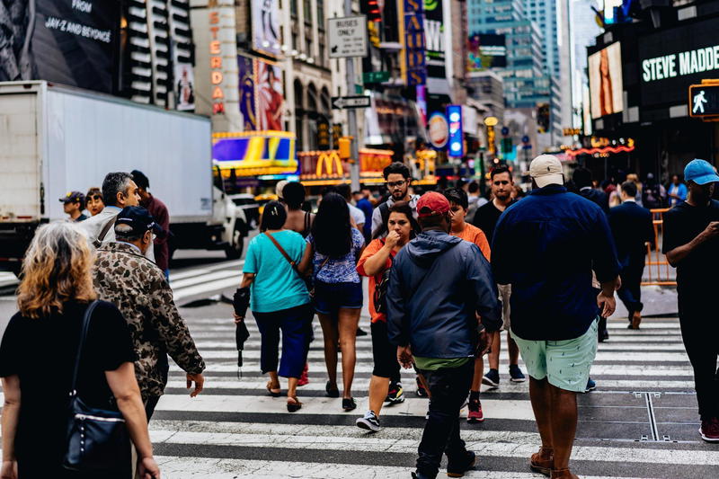 A crowd of people crossing the street in times square.