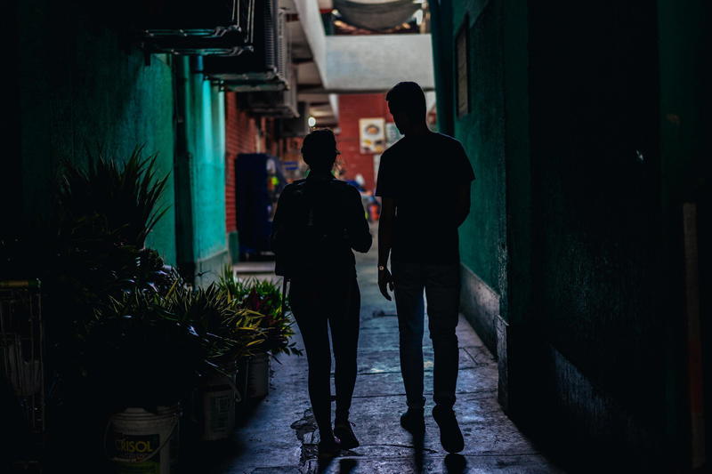 Two people standing in a dark alley.