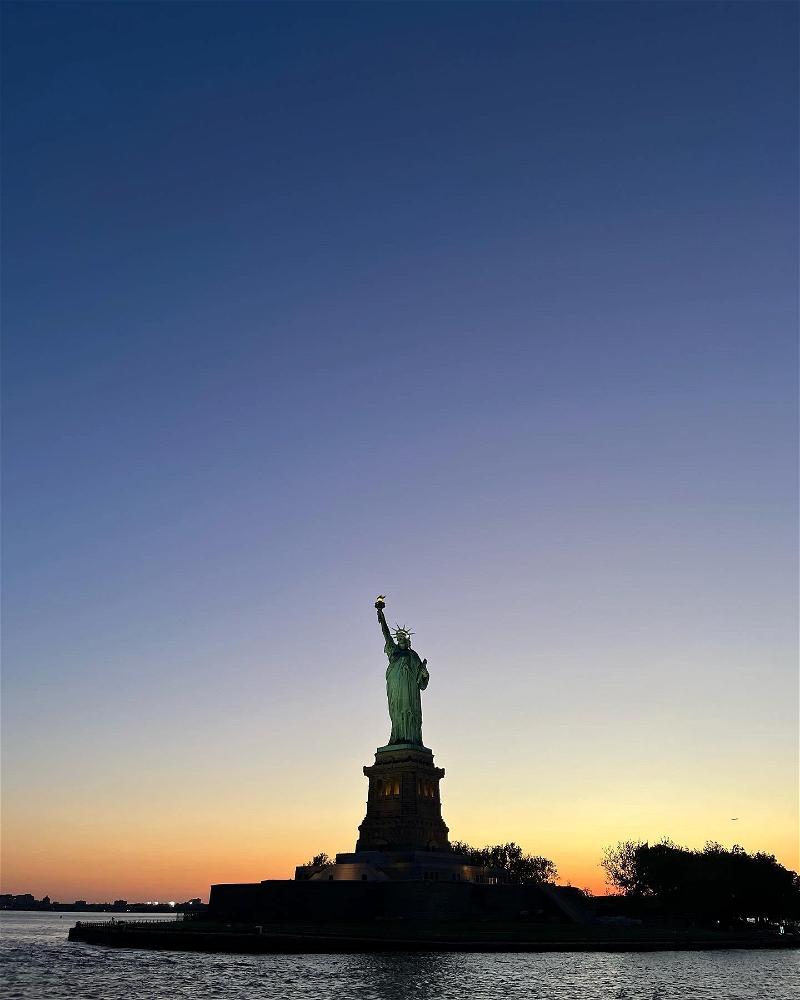 The statue of liberty at sunset in new york city.