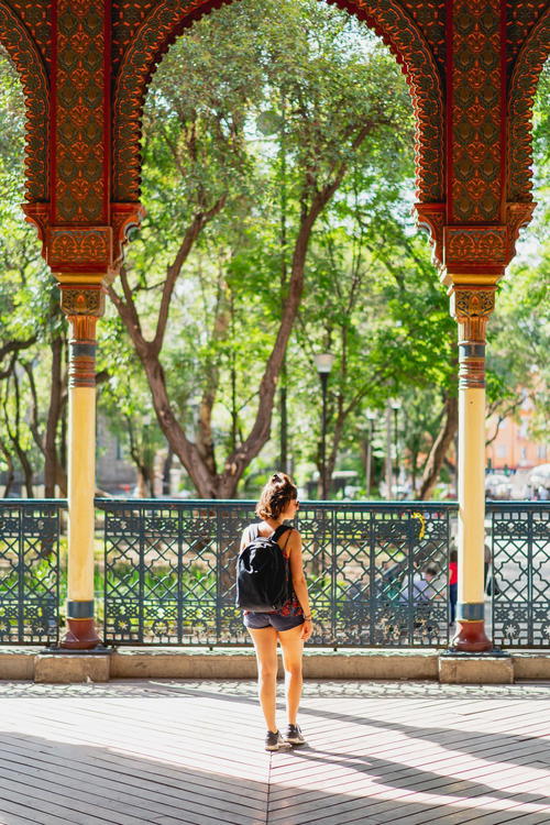 A woman walking through a park with a backpack.