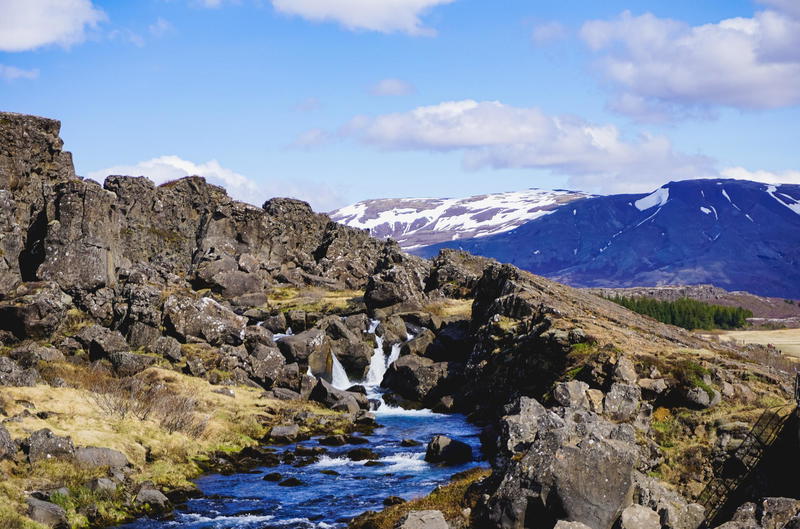 A stream running through a rocky area with mountains in the background.