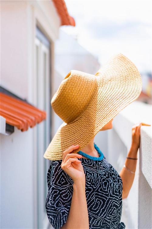 A woman wearing a hat on a balcony.