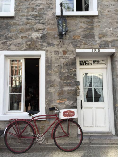 A red bicycle leaning against a stone building.