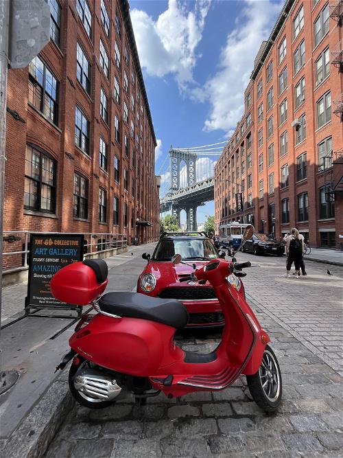 A red scooter parked in front of a brick building.