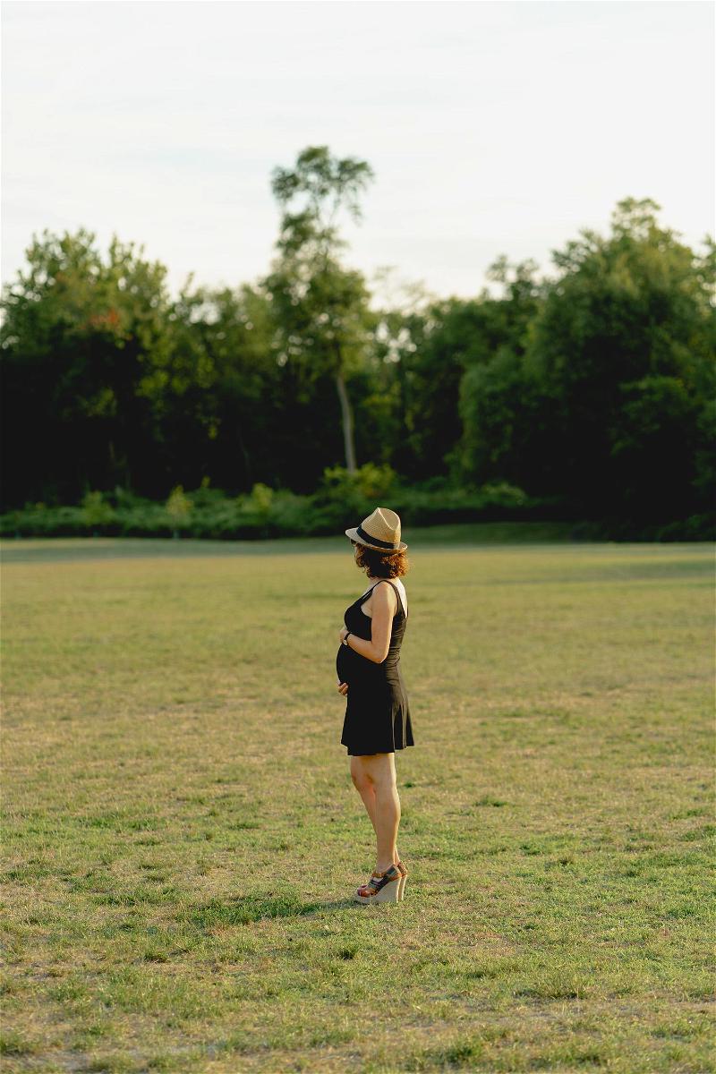 A woman in a black dress standing in a field.