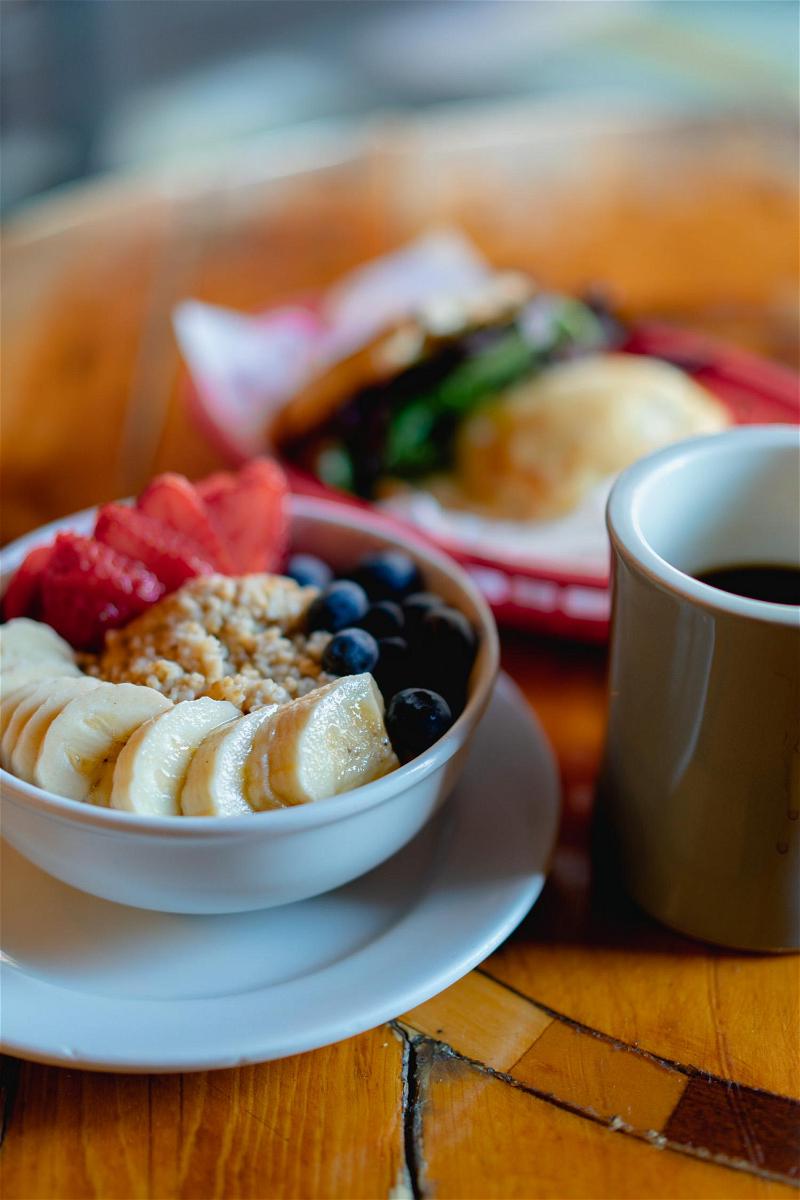 A bowl of fruit and a cup of coffee on a table.