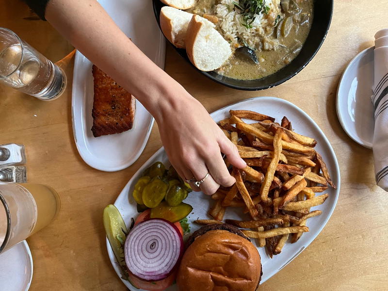 A plate of french fries and a burger on a wooden table.