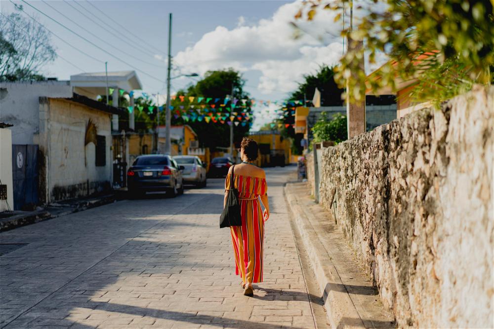 A woman walking down a street in a colorful dress.
