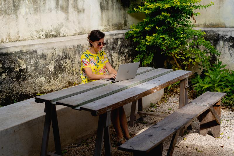 A woman sitting at a wooden table with a laptop.