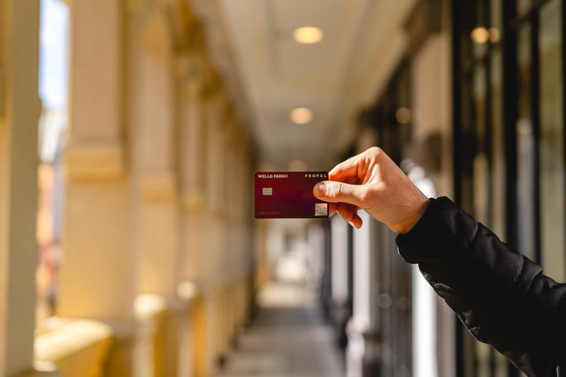 A person holding up a credit card in a hallway.