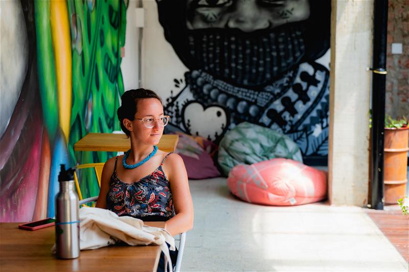 A woman sitting at a table in front of a mural.