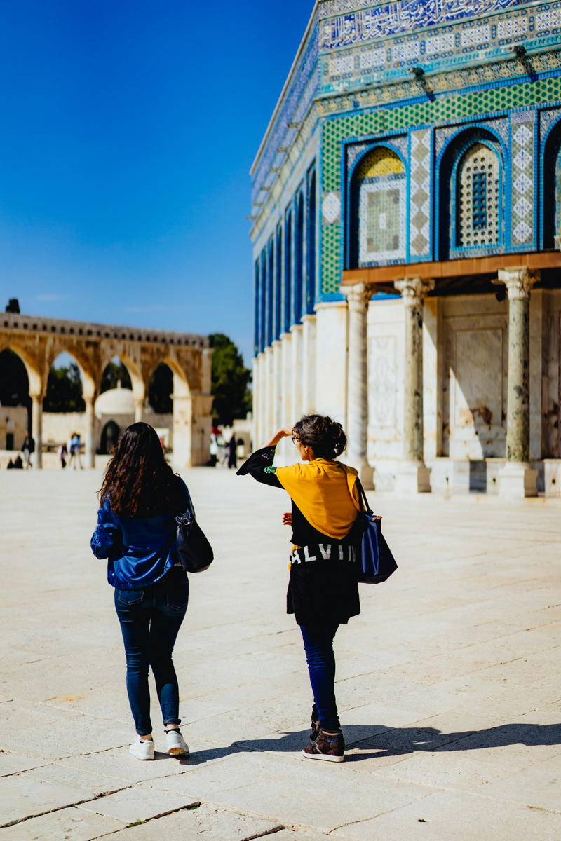 Two women walking in front of a building.