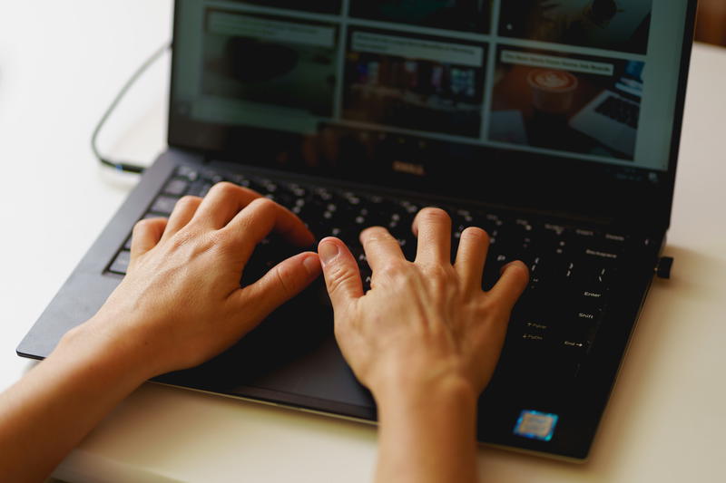 A woman's hands typing on a laptop computer.