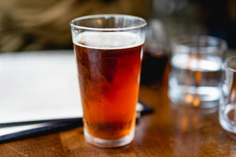 Frosted beer glass next to white menus on a wooden table with glasses of water