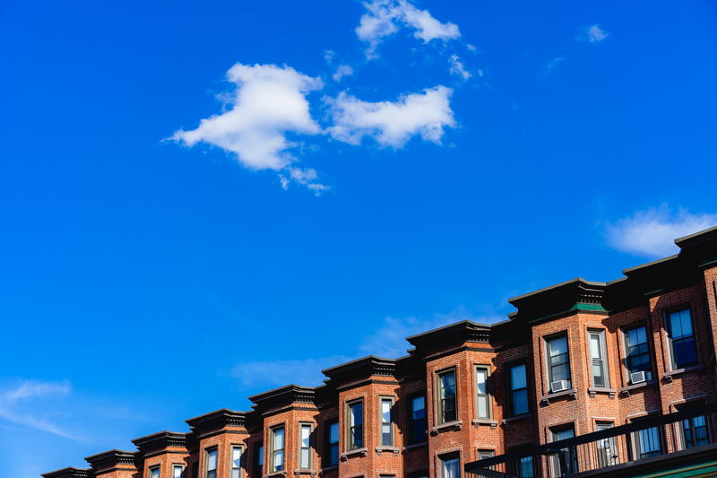 Blue sky and white clouds above historic rowhouses in Back Bay Boston neighborhood