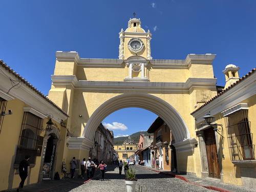 A yellow building with a clock tower in front of it.