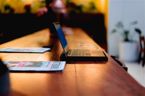 A laptop sitting on a wooden table.