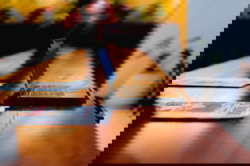 A laptop sitting on a wooden table.