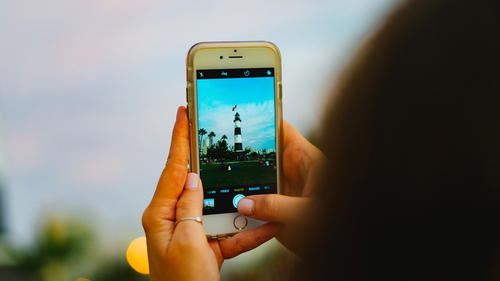 A woman is taking a picture on her cell phone.