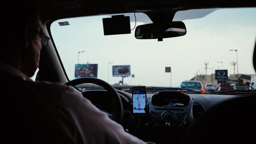 A man driving a car with a cell phone in his hand.