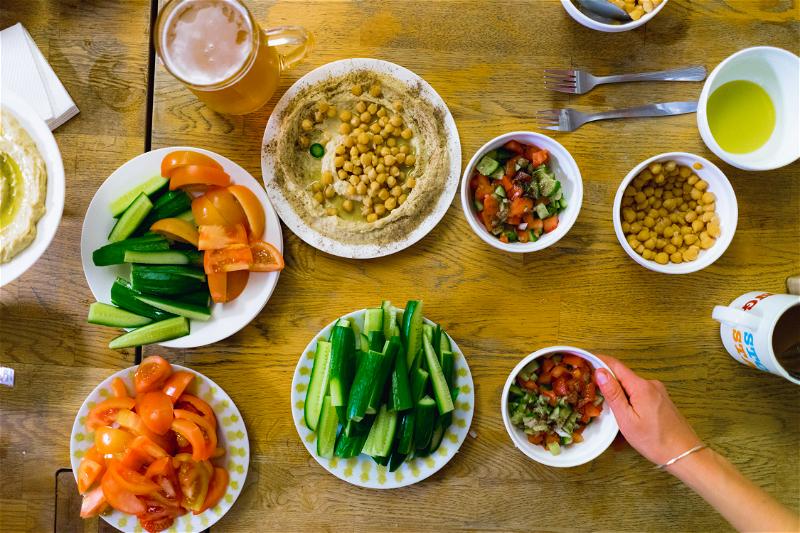 Spread of Israeli salads and vegetables, including cucumbers, tomatoes, Israeli salad and fresh hummus with chickpeas on top in Jerusalem, Israel.
